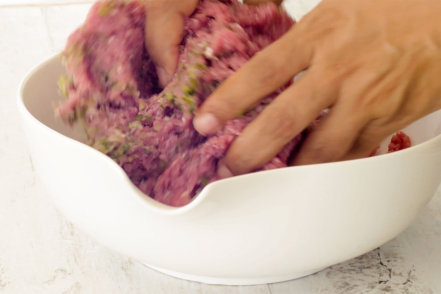 Mezclando la carne y el sazón con las manos
